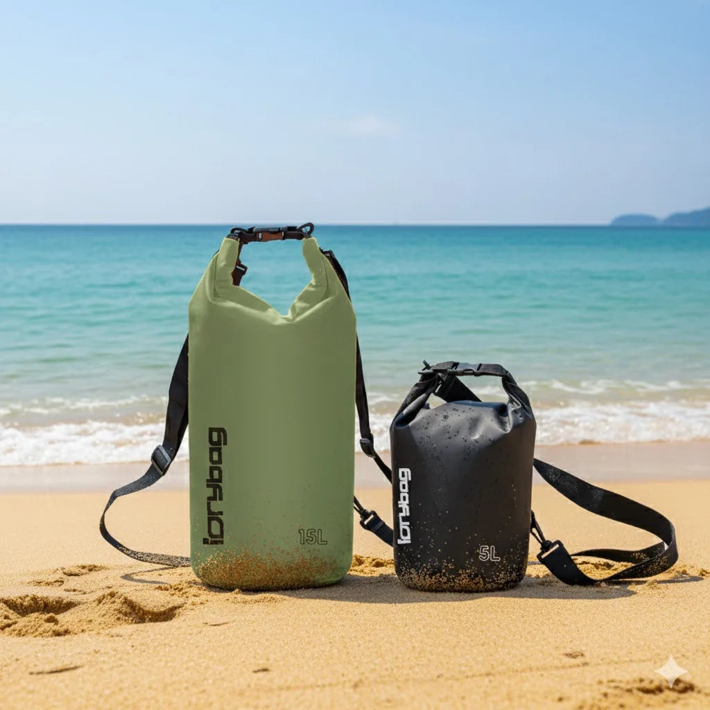 Green and black roll-top dry bags with shoulder straps on a sandy beach