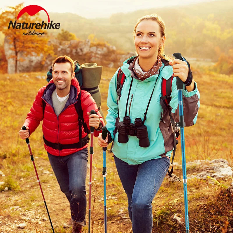 Two hikers smiling with trekking poles on an autumn trail
