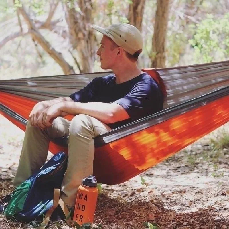 Man sitting in an orange and gray hammock outdoors