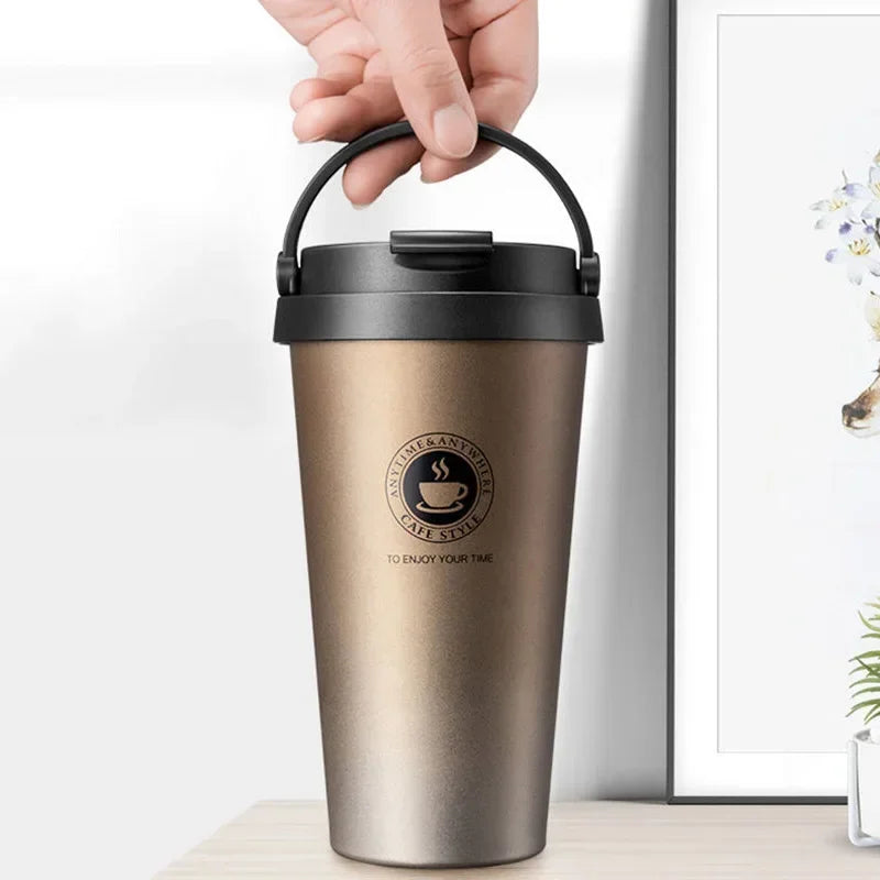 Hand holding a gold travel mug by a lid handle