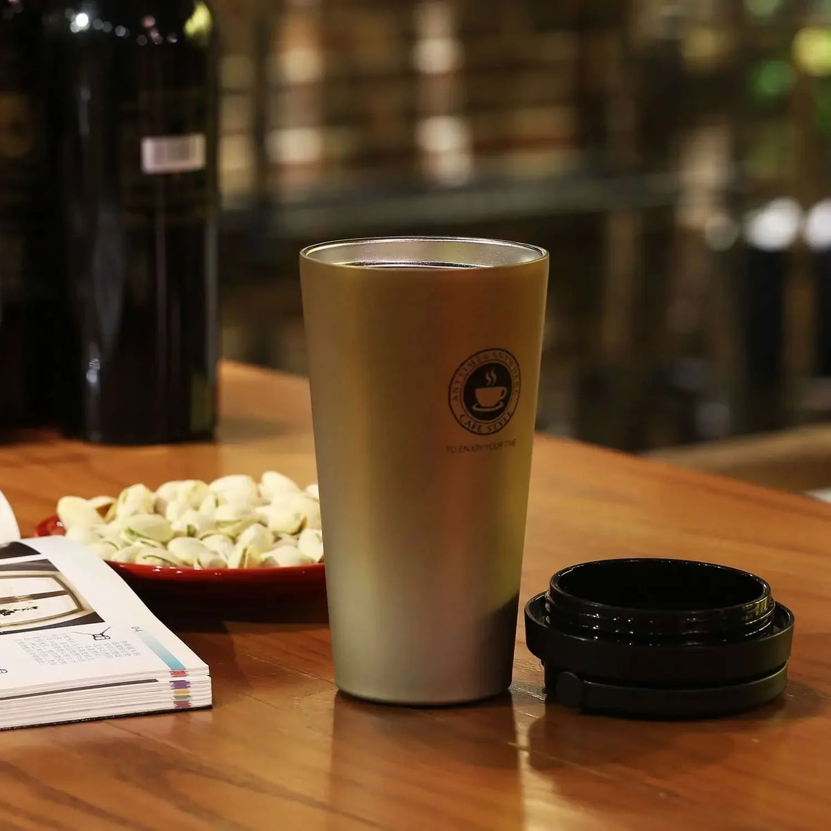 Gold travel mug with the lid off on a wooden table